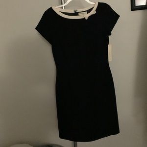 Black dress with cream collar accented with a bow. Zip back and two slits